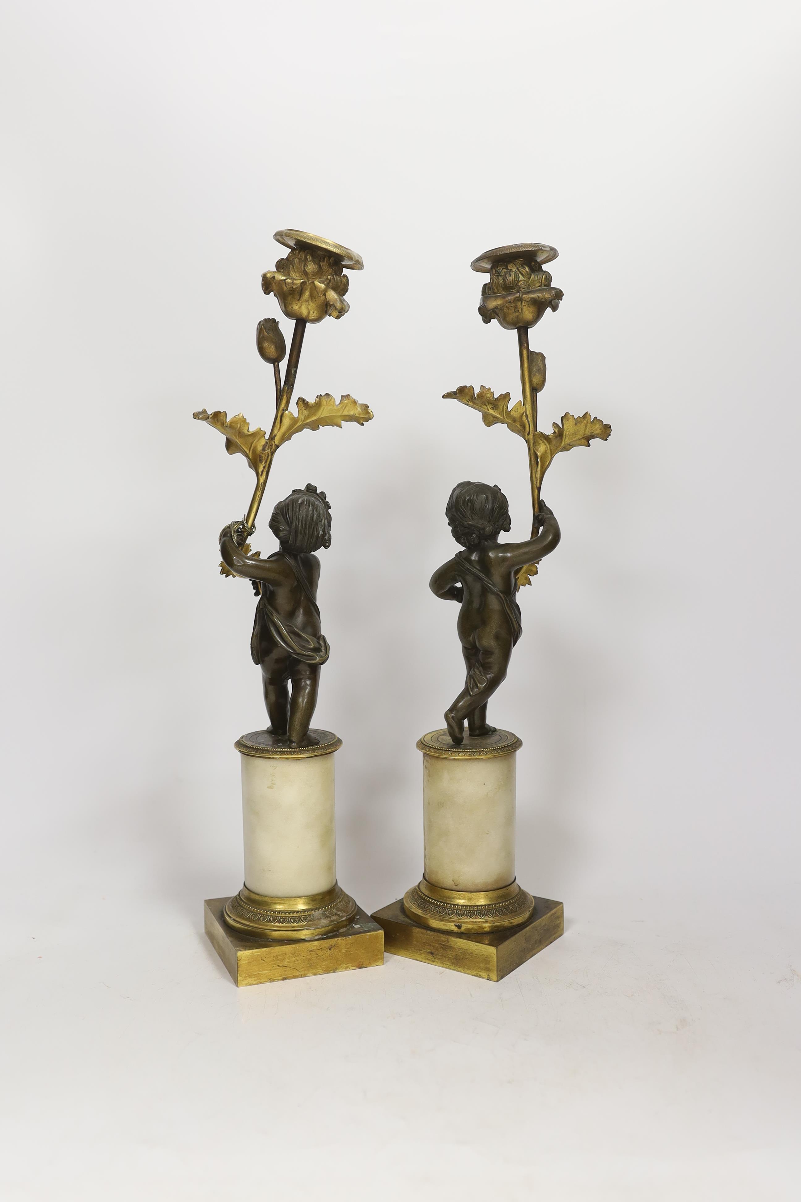 A pair of Regency bronze and ormolu amorini candlesticks, with white marble plinths, 40cm. Condition - fair